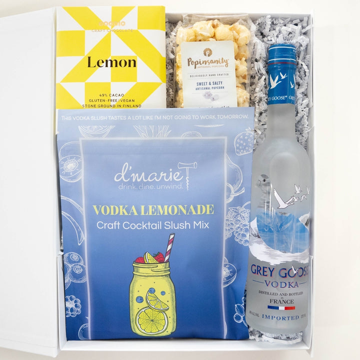 Photograph of a curated cocktail gift box featuring a frosted bottle of Grey Goose Vodka and a d&
