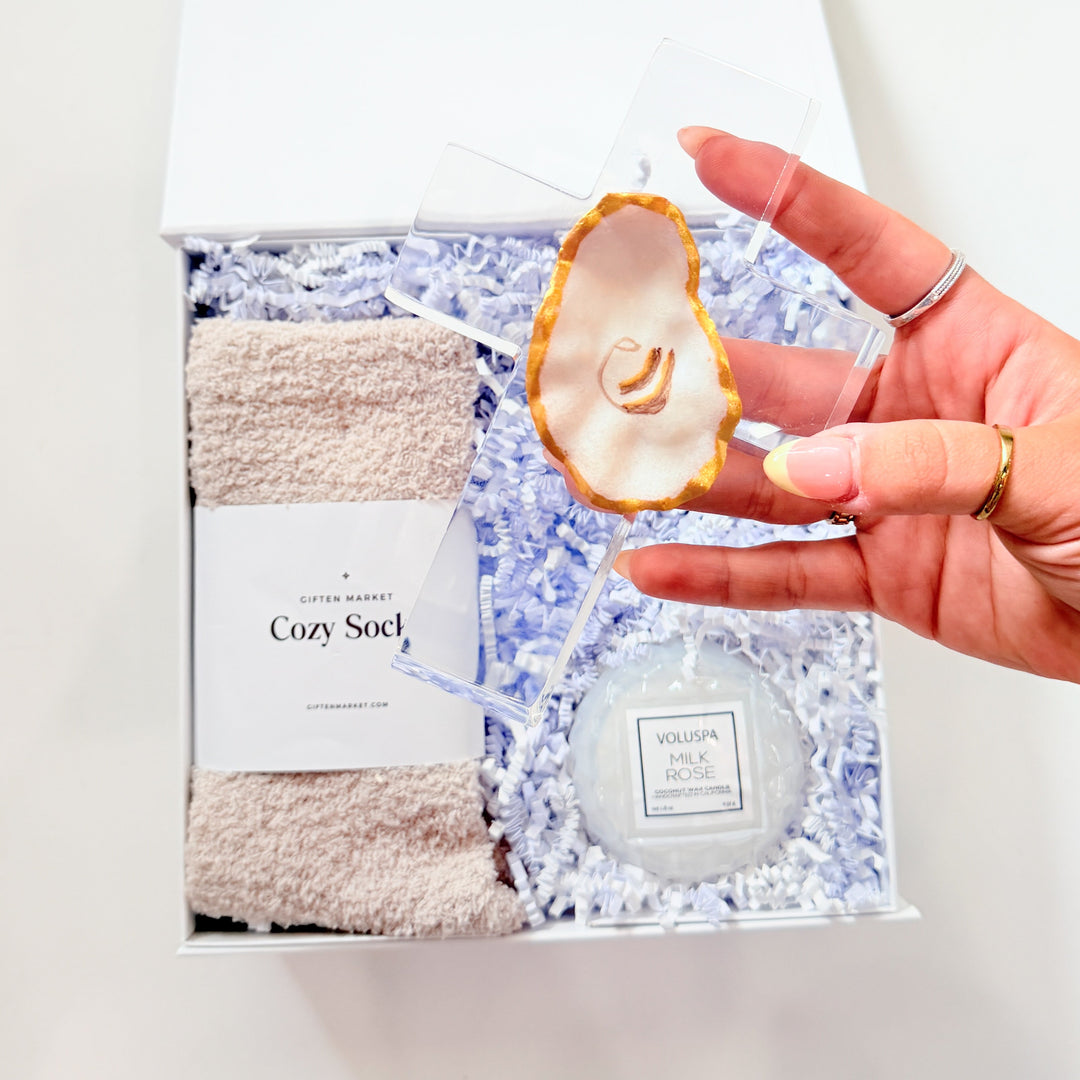 Hand holding a bath product set with a towel and loofah on a white background