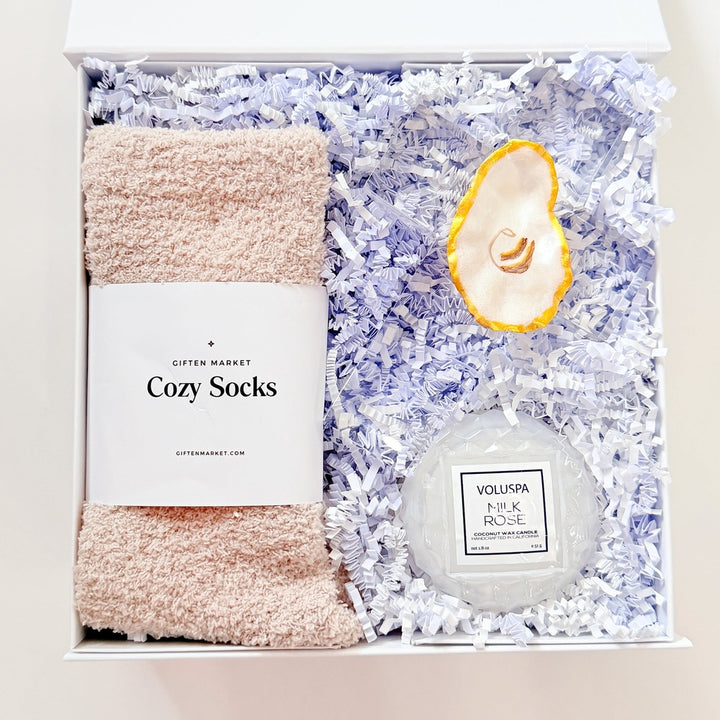 Gift set with socks, bath bomb, and candle in a box on a white background