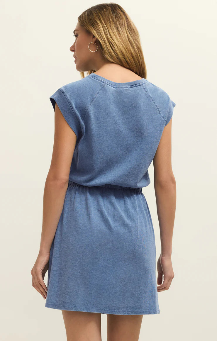 Studio photograph of a woman wearing a heathered blue cap-sleeved dress with an elasticized waist and a gold hoop earring against a neutral studio backdrop