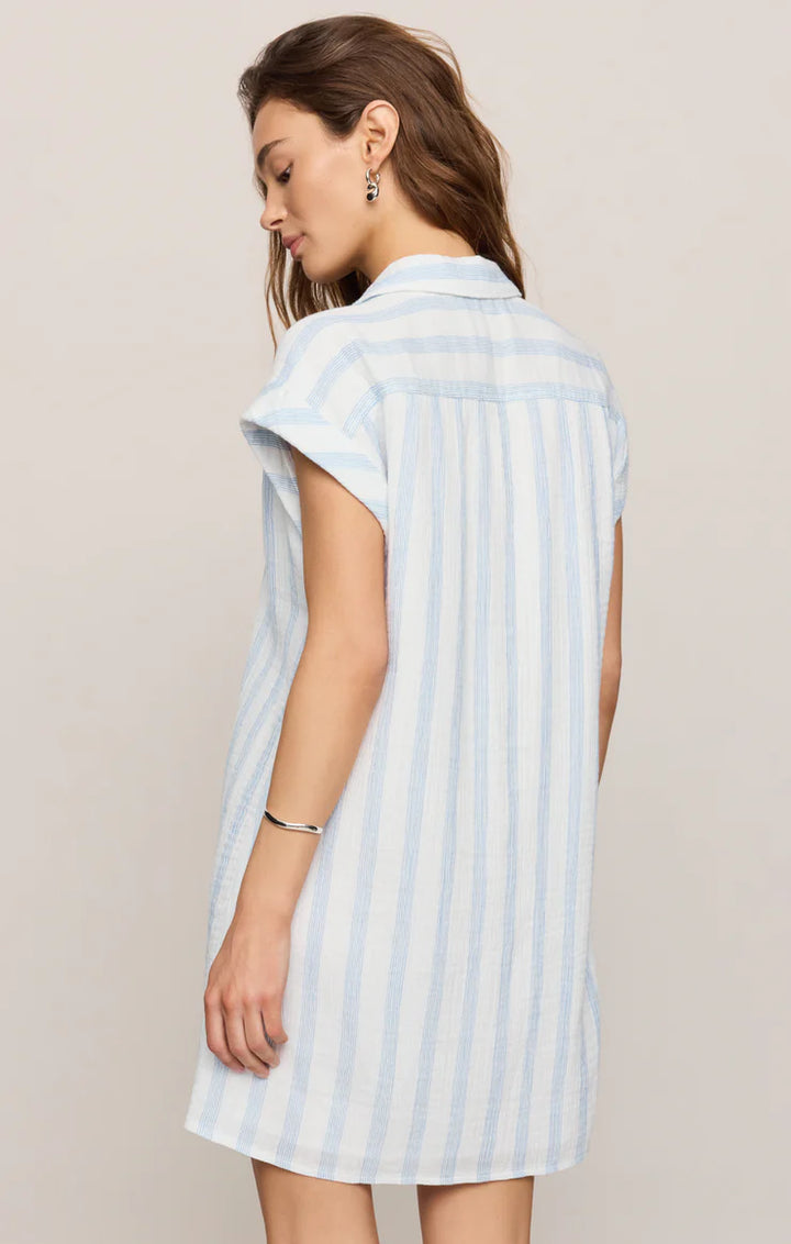 Woman wearing a light blue and white striped dress against a beige background