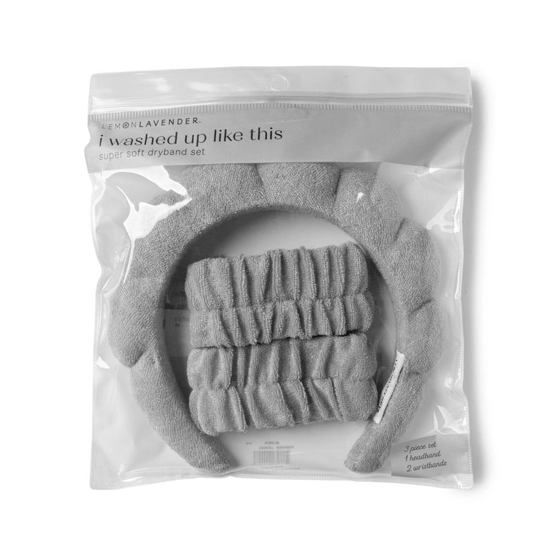 Product photograph by Lemon Lavender of a plush gray dryband set inside clear packaging featuring a puffy padded headband, two ruffled elastic wristbands, and the brand slogan i washed up like this