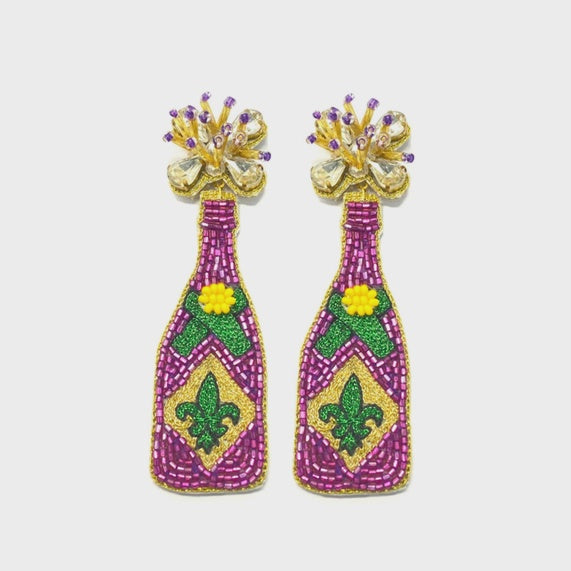 Hand-beaded earrings featuring New Orleans Mardi Gras champagne bottles adorned with the iconic fleur-de-lis and vibrant purple, green, and gold patterns with sparkling crystal-burst corks