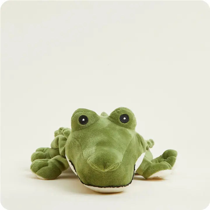 Plush toy of a green crocodile in a studio setting featuring textured olive green fabric, a soft white underbelly, and large embroidered black eyes