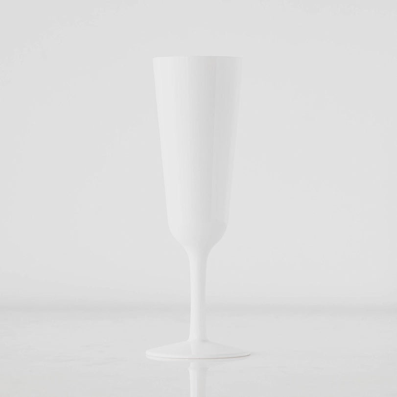 A photograph of an opaque white champagne flute in a minimalist studio setting featuring a long slender stem and a seamless high-gloss finish
