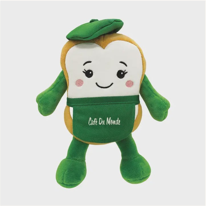 Plush toy by Café Du Monde of a smiling beignet mascot from the New Orleans landmark wearing a green beret and a branded green apron with embroidered pink cheeks