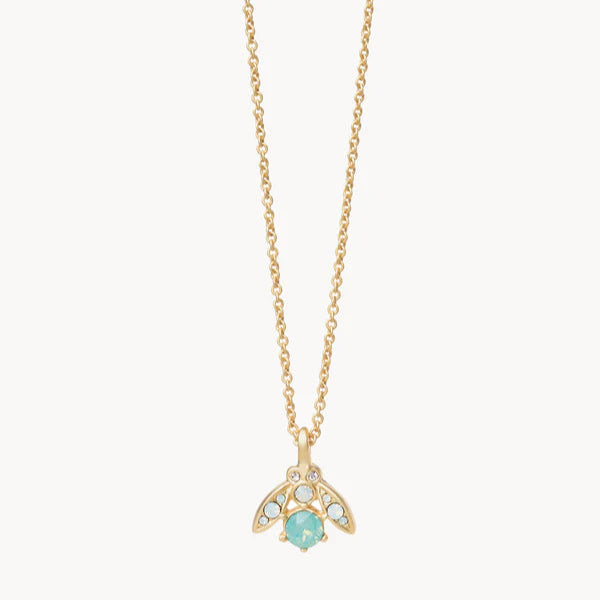 Gold-toned jewelry by Catherine Popesco featuring a firefly pendant necklace centered on a white background with a faceted mint green crystal and iridescent opal-styled stones along the wings