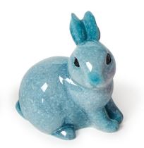 Ceramic figurine of a sitting rabbit against a white background featuring a glossy mottled blue glaze and small dark eyes