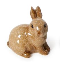 Glazed stoneware rabbit figurine by Lisa Larson on a white background featuring a speckled tan glaze, dark almond eyes, and a reflective glossy finish