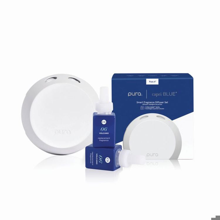 Product photography by Pura and Capri Blue showcases a smart fragrance diffuser set featuring two navy blue square glass Volcano refills and a sleek white circular device on a plain white studio background