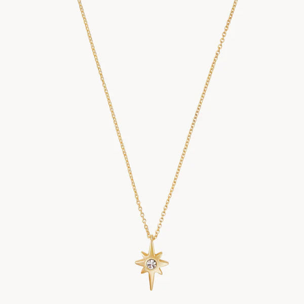 Gold jewelry featuring a North Star pendant necklace on a white background with an eight-pointed starburst design and a central round clear crystal on a delicate cable chain