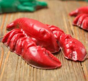 Handcrafted molded lobster figurine on a rustic wooden tabletop featuring a vibrant scarlet glossy finish, intricate segmented tail, and prominent pincers