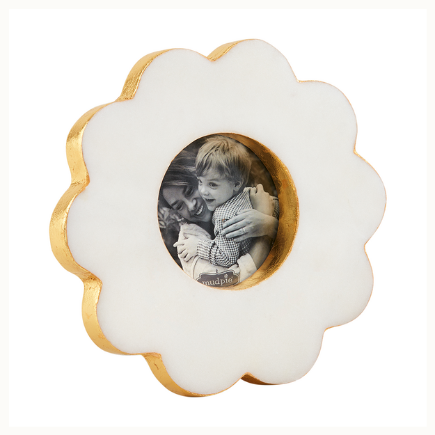 Marble and gold leaf picture frame by Mud Pie featuring a scalloped flower-shaped design on a white background with gold-gilded edges and a circular black-and-white photo of a smiling mother and child