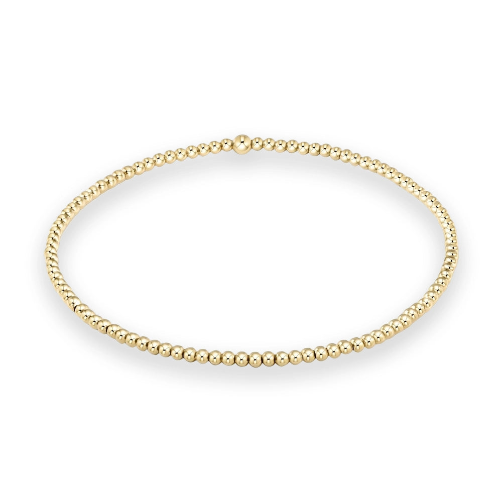 Gold beaded bracelet featuring a continuous loop of small polished spheres and a single larger central bead displayed against a clean white background