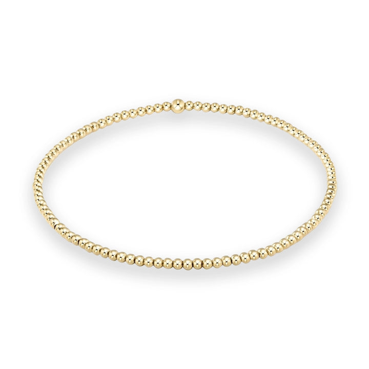 Gold beaded bracelet featuring a continuous loop of small polished spheres and a single larger central bead displayed against a clean white background