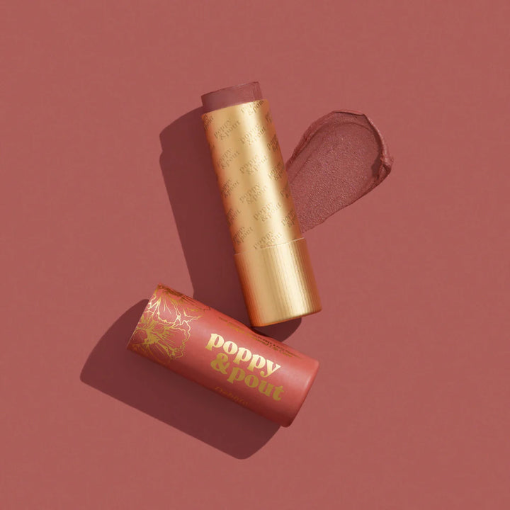 Product photography by Poppy &amp; Pout of a mauve tinted lip balm and cardboard cap on a monochromatic dusty rose background featuring a thick textured product swipe and gold foil floral illustrations