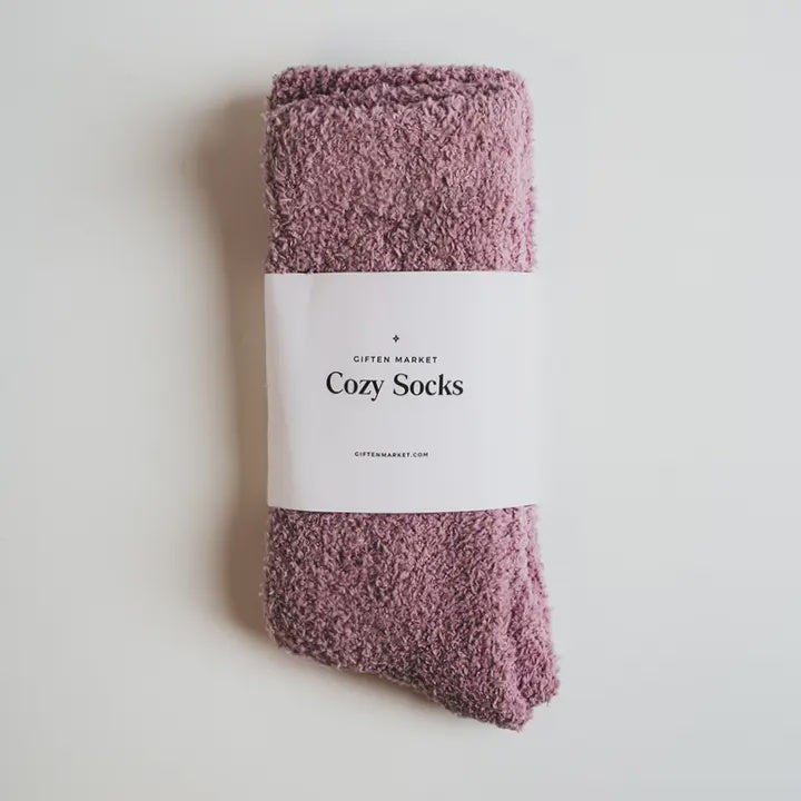 Product photograph by Giften Market of a pair of mauve fuzzy socks on a white background featuring a plush chenille texture and a minimalist white paper band labeled Cozy Socks