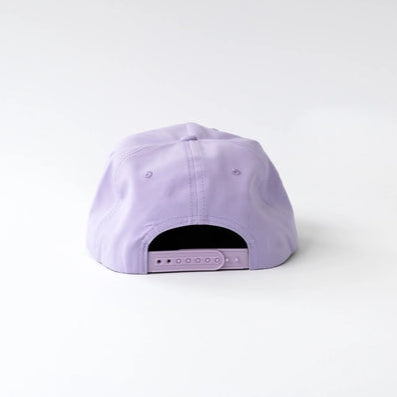 Studio photograph of a lavender cotton snapback cap showing the adjustable plastic back strap and matching embroidered eyelets against a plain white background