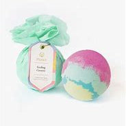 Product photograph of Musee Feeling Groovy bath bombs on a white backdrop featuring one unwrapped sphere with vibrant pink, mint green, and yellow horizontal layers next to a second bomb wrapped in mint green tissue paper with a scalloped tag