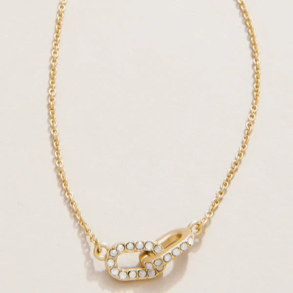 Gold-toned jewelry necklace featuring two interlocking oval pavé links encrusted with shimmering white crystals and a delicate cable chain against a neutral studio background