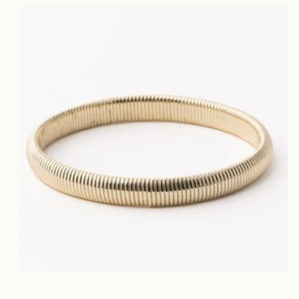 Gold-toned metal flexible bracelet showcasing a detailed vertical ribbed texture and a polished circular design against a neutral white background