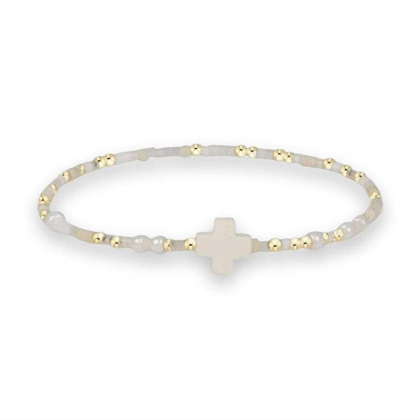 Beaded jewelry bracelet featuring a central matte white cross charm accented by small gold metallic spheres and translucent milky-white stone beads on a plain white background