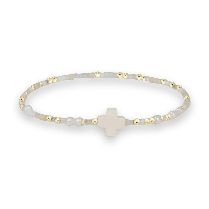 Beaded jewelry bracelet featuring a central matte white cross charm accented by small gold metallic spheres and translucent milky-white stone beads on a plain white background