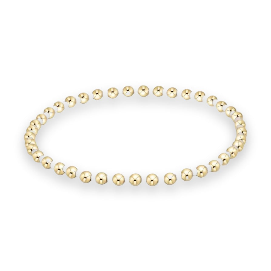 Beaded jewelry bracelet featuring high-polish yellow gold spherical beads alternating with small matte white spacer beads arranged in a circular loop against a minimalist white background