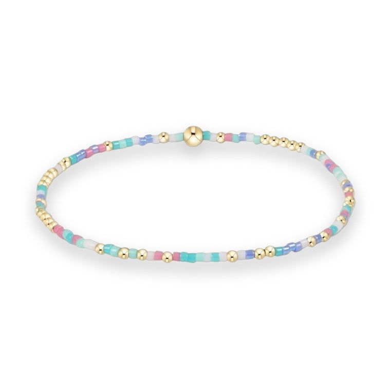 Handcrafted beaded jewelry by Erimish featuring a colorful stretch bracelet with pastel pink and turquoise seed beads accented by polished gold spherical spacers and a prominent central gold bead against a white background