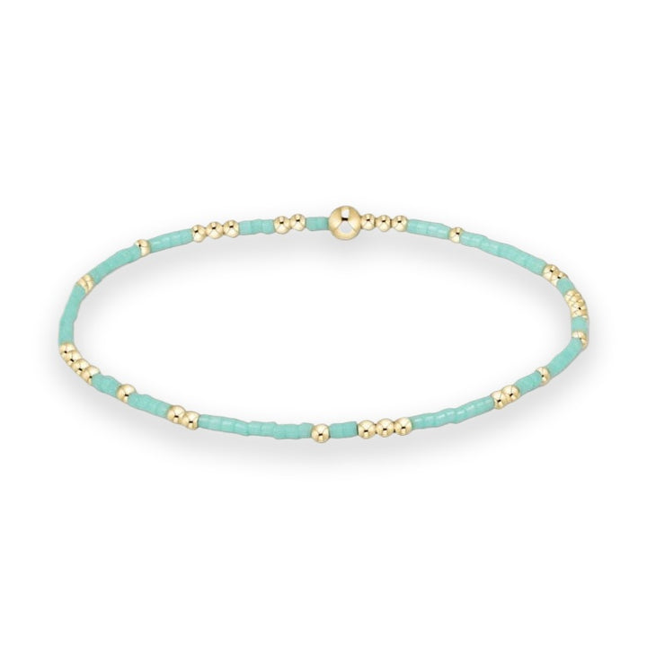 Handcrafted beaded jewelry bracelet featuring alternating turquoise seed beads and polished gold spheres with a larger central focal bead on a white background