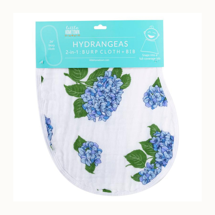 Little Hometown cotton muslin 2-in-1 burp cloth and bib featuring a vibrant pattern of blue and periwinkle hydrangea clusters with serrated green leaves on white fabric beneath a teal branded header card