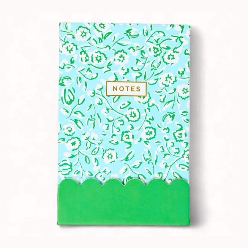 Lilly Pulitzer printed stationery notepad featuring a light blue background with white and green floral illustrations, a gold-bordered NOTES box, and a bright green scalloped bottom edge against a white background