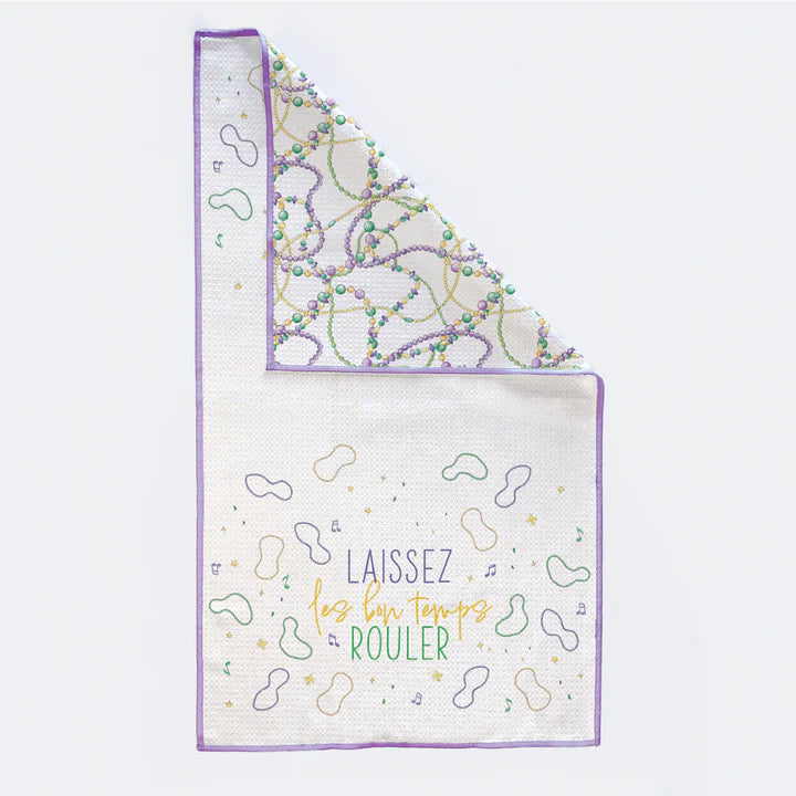 Waffle weave microfiber kitchen towel featuring a New Orleans Mardi Gras theme with the slogan Laissez les bon temps rouler, vibrant purple, green, and gold beads, and whimsical musical notes on a white textured background