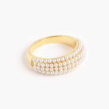 Gold-tone jewelry photography of a polished dome ring featuring four rows of small lustrous white pearls set against a clean white background