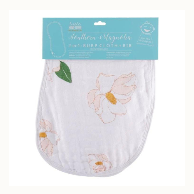 Textile by Little Hometown Southern Magnolia 2-in-1 burp cloth and bib featuring delicate pink blossoms, golden-yellow centers, and a single green leaf on white muslin fabric against a white background with its blue branded header card