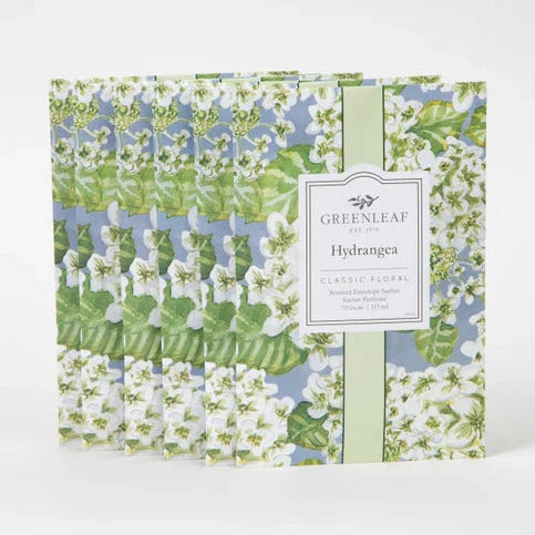 Product photograph by Greenleaf showcasing six Hydrangea scented envelope sachets on a plain white background featuring a pattern of delicate white blossoms, vibrant green leaves on a soft blue field, and a classic central white brand label