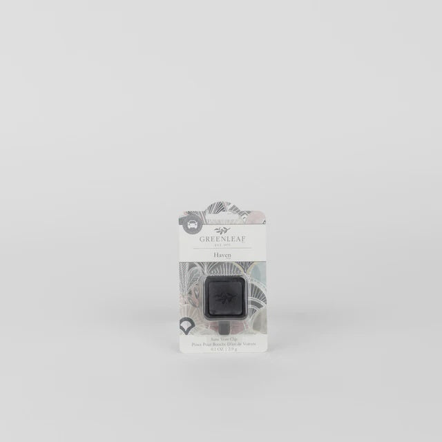 Product photography by Greenleaf of a Haven Auto Vent Clip on a minimalist grey background featuring a square black diffuser, intricate grey and white botanical packaging, and the company logo at the top