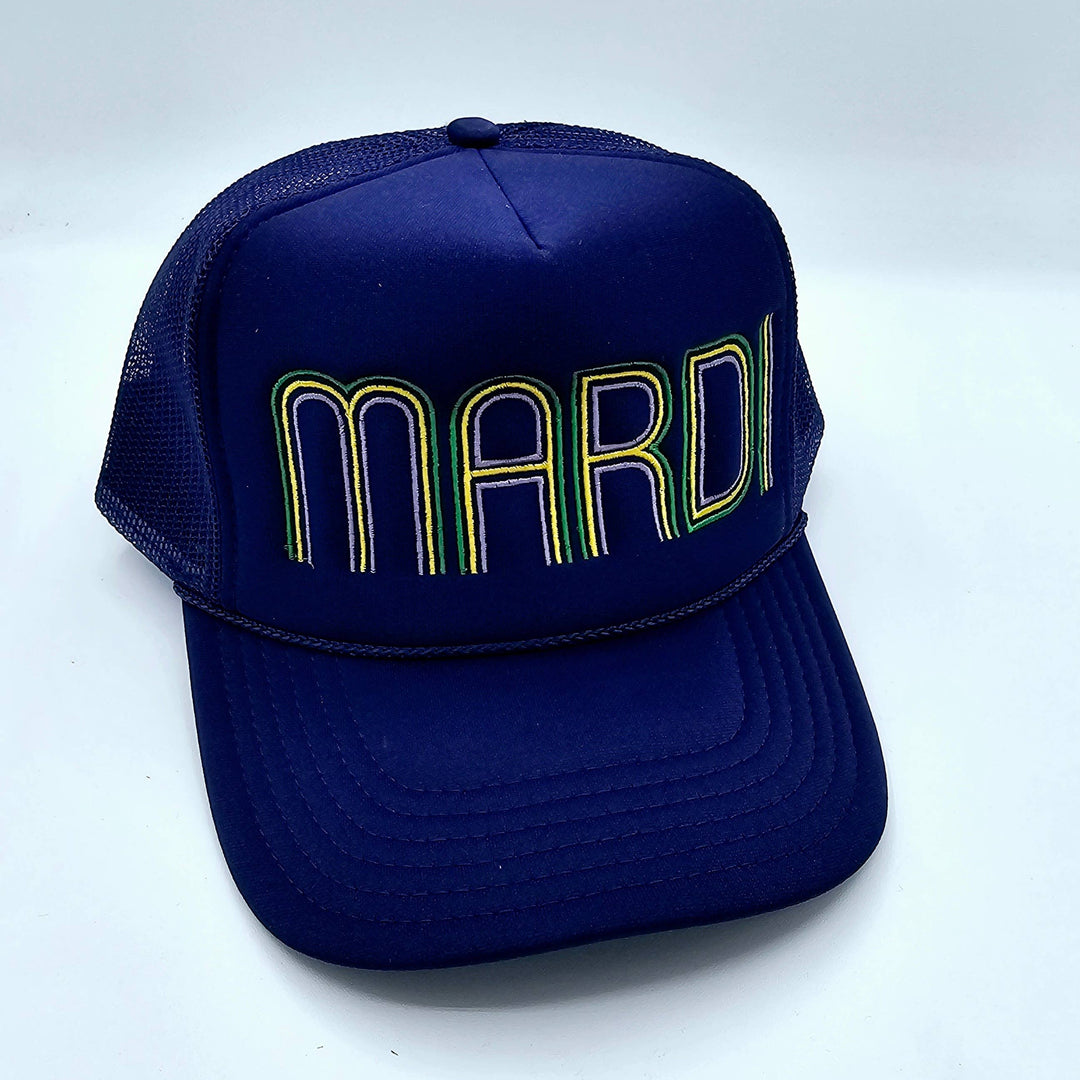 Photograph of a navy blue mesh-back trucker hat featuring the word MARDI in stylized purple, green, and yellow embroidery with a decorative braided rope detail across the base of the crown offset by a clean white background