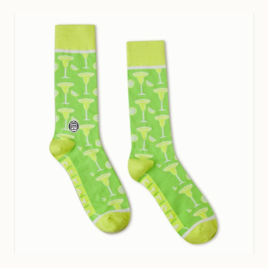 Knitted crew socks by ED Ellen DeGeneres featuring a pair of lime green socks with a repeating pattern of yellow margarita glasses and lime wedges, accented by bright yellow-green heels and toes on a white background