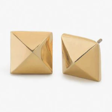 Gold-toned metal jewelry featuring a pair of pyramid stud earrings with polished reflective surfaces and sharp four-sided geometric peaks displayed on a minimalist white background