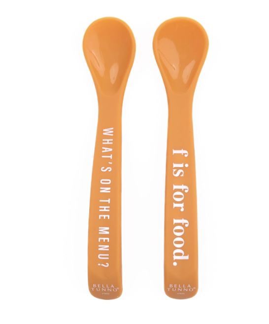 Silicone baby spoons by Bella Tunno featuring two vibrant orange feeding utensils on a white background with white typographic lettering reading WHAT'S ON THE MENU? and f is for food along with brand logos at the base of the flat handles