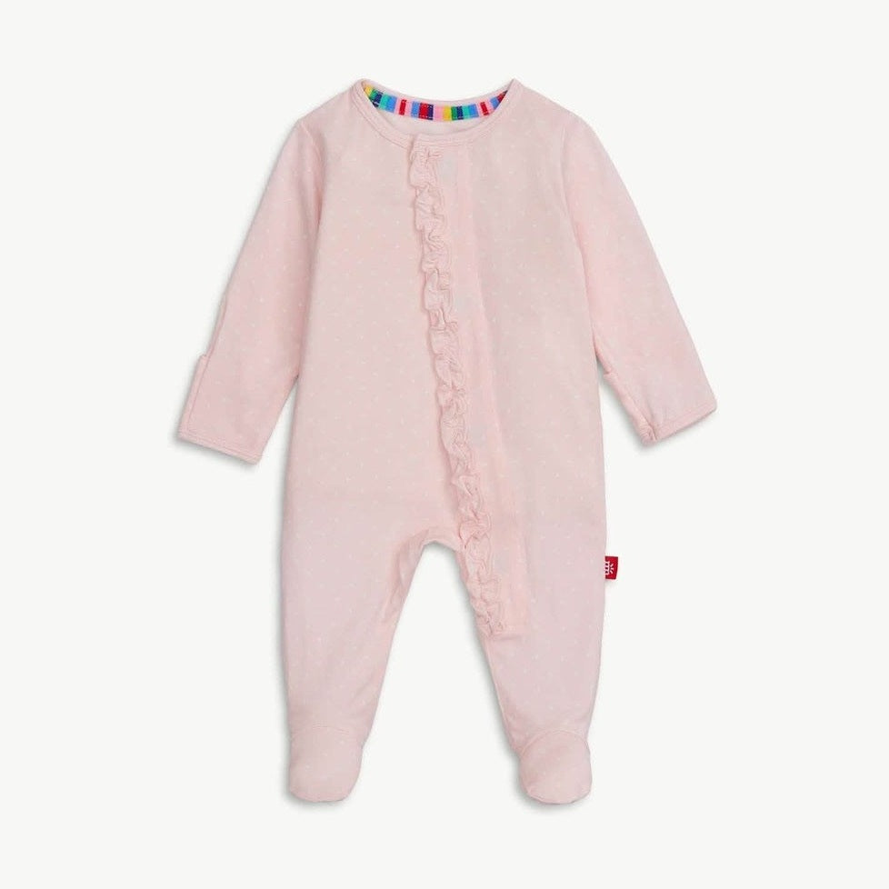 Product photograph of a pale pink baby footed sleeper centered on a white background featuring a delicate ruffle along the front zipper, a rainbow-striped inner neckline, and tiny white polka dots throughout the fabric