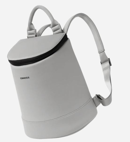 Product photograph by Corkcicle of a light grey insulated backpack cooler against a white background featuring a sleek cylindrical bucket design, a contrasting black zipper closure, and a padded top handle
