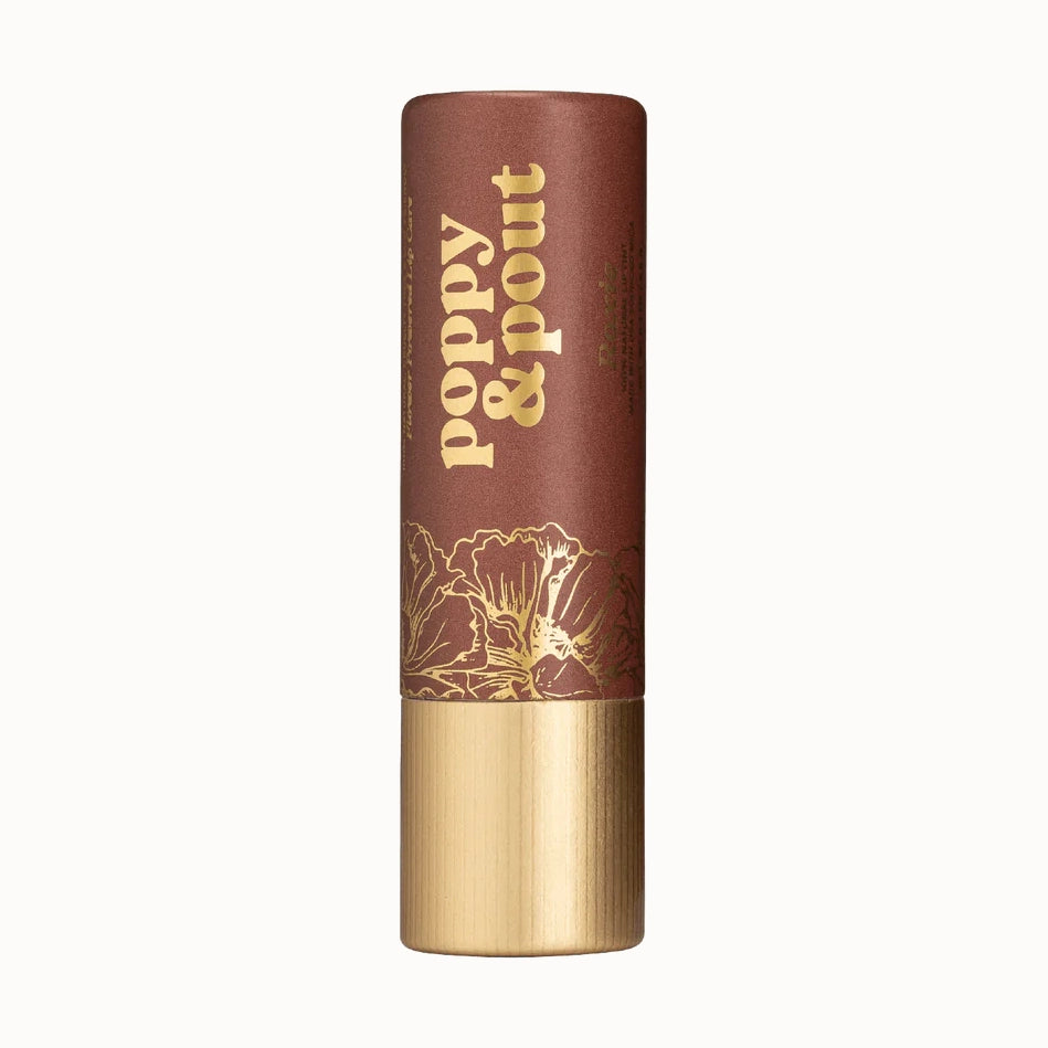 Studio photograph of a Poppy & Pout lip tint tube featuring earthy terracotta cardboard packaging with cream vintage lettering, intricate gold floral line art, and a textured metallic gold base
