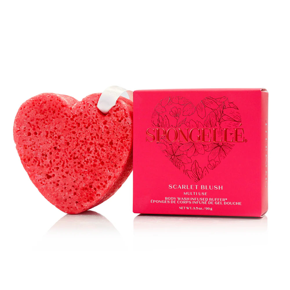 Spongellé product photography of a textured scarlet heart-shaped body wash buffer with a white hanging ribbon loop next to its matching floral-patterned box on a white reflective background