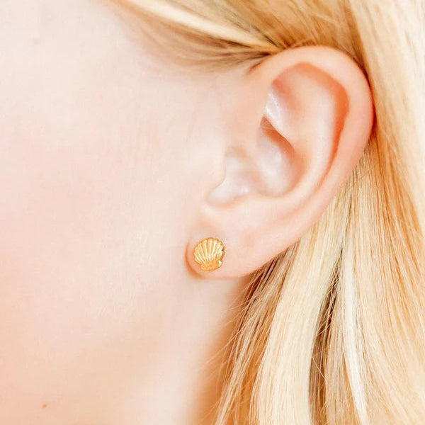 Digital photograph of a gold scallop shell stud earring worn on a woman&
