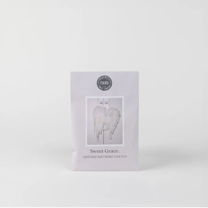 Product photograph by Bridgewater Candle Company of a Sweet Grace scented sachet centered on a minimalist grey background featuring the brand’s circular logo, a central image of white feathery angel wings, and fine black typography on pale lavender-grey paper packet