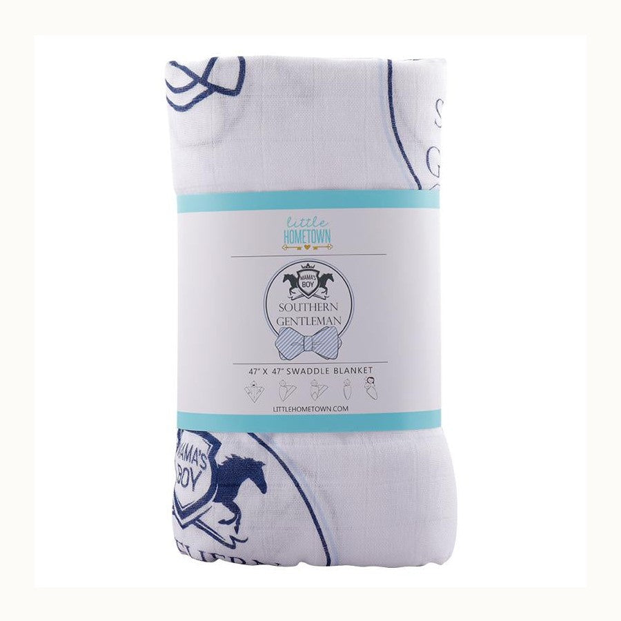Cotton muslin swaddle blanket by Little Hometown featuring a Kentucky-themed pattern with navy blue horse silhouettes, the Churchill Downs twin spires icon, and a Mama's Boy crest with a striped bow tie label