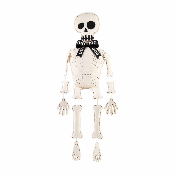 Fabric hanging skeleton decoration features a cream-colored body with black dashed bone outlines, a black ribbon bow tie printed with the word BOO, and articulated dangling limbs set against a plain white background