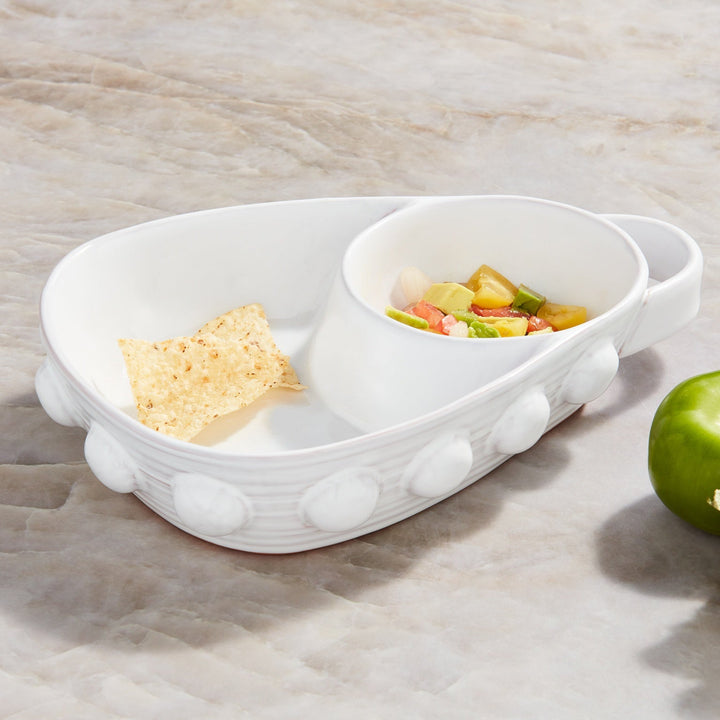 Ceramic stoneware serving bowl by Mud Pie on a marble countertop featuring a signature beaded exterior, a single golden tortilla chip, and a colorful medley of diced avocado and tomato salsa